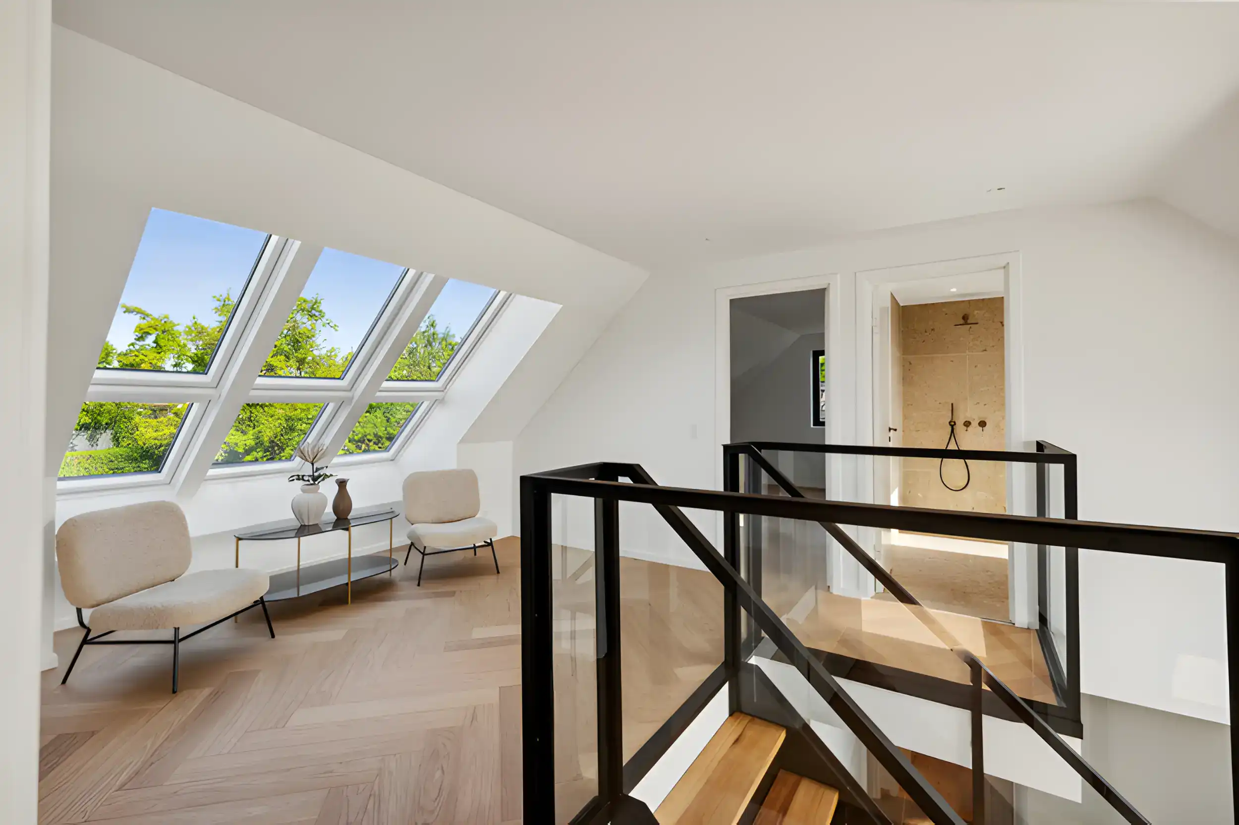 Hjemmeindretning med store vinduer og moderne trappe i lyst rum.